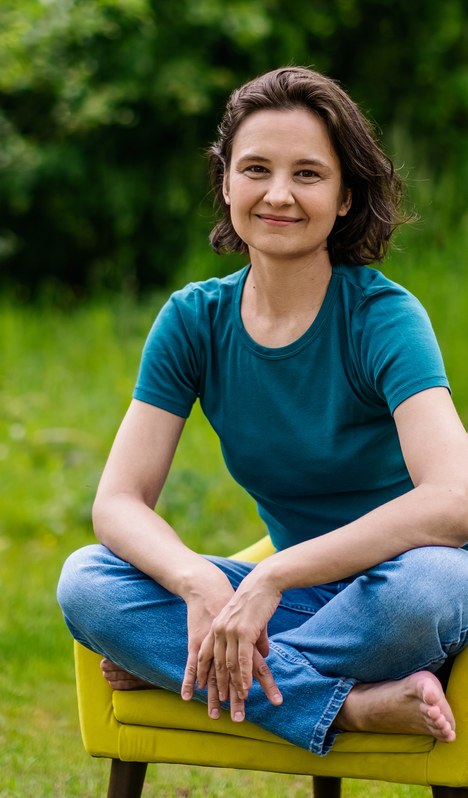 Magdalena Kosak, terapeutka Techniki Bowena, siedzi w pozycji skrzyżnej na żółtym fotelu